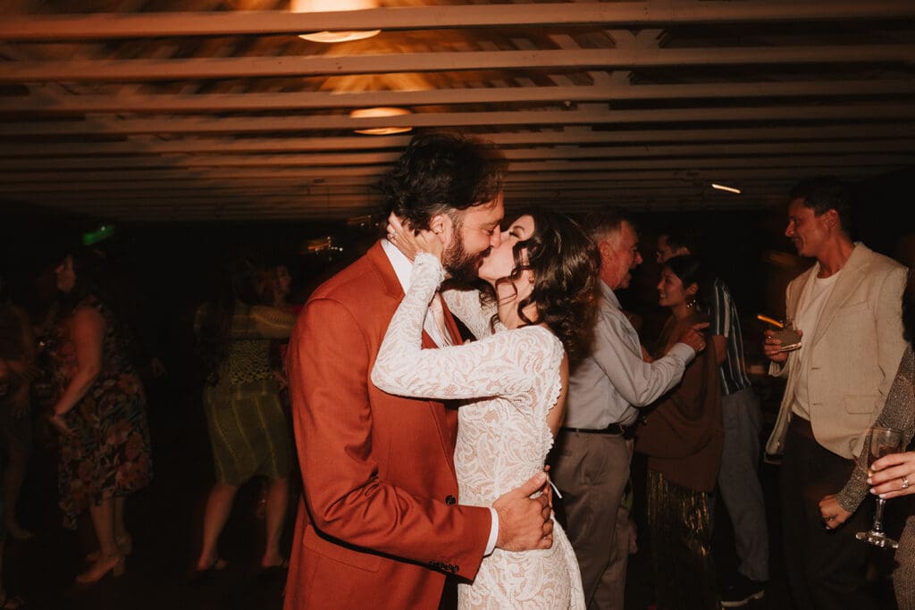 cute portrait of the newlyweds kissing at their wedding reception party